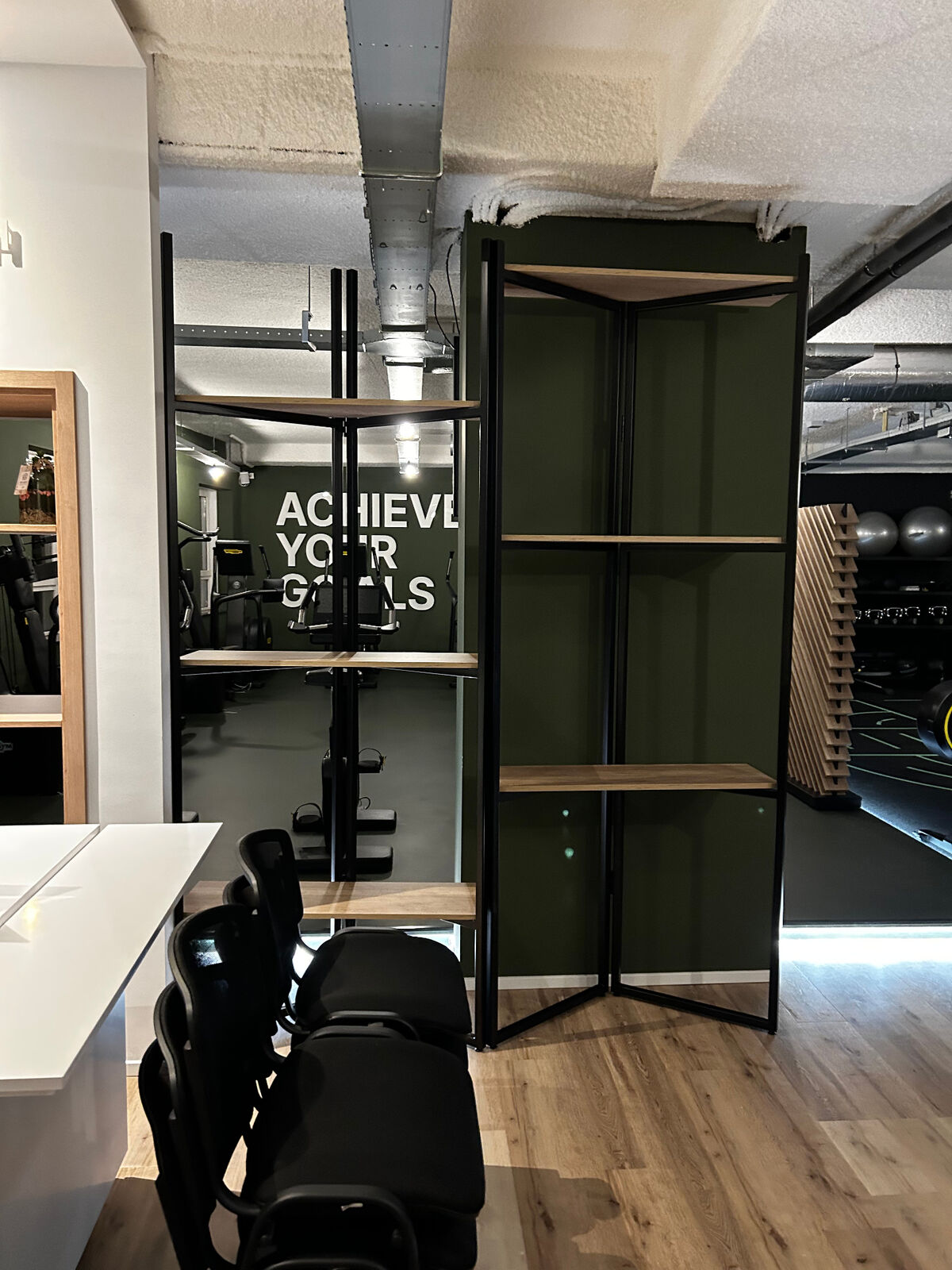 Maatwerk zwart-stalen open kast met houten planken — installatie van klimaat­leidingen zichtbaar boven