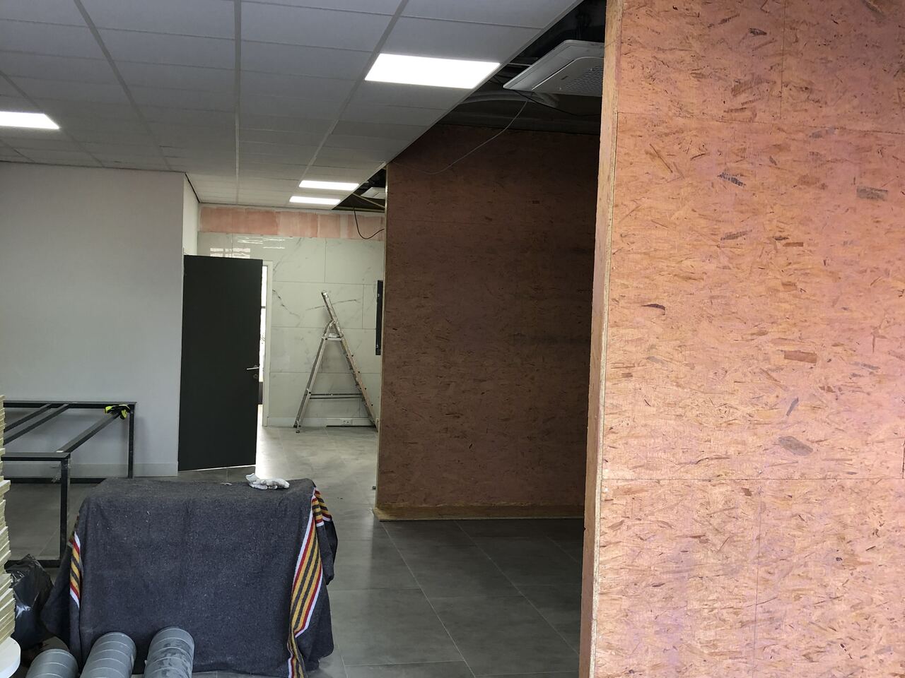 Bouwfase — OSB scheidingswand met zichtbare plafond cassette airco en aangevoerde ductwork