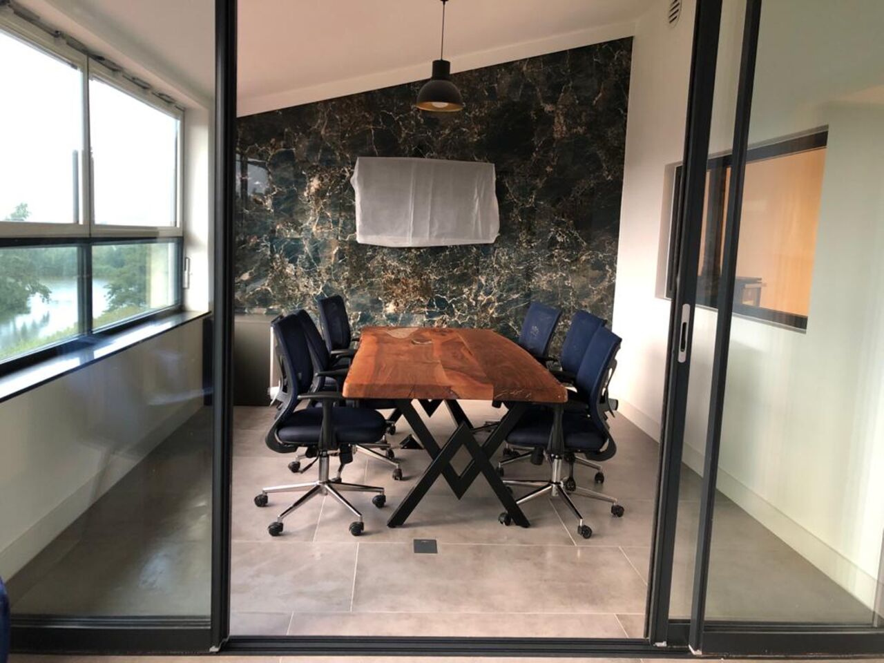 Eindresultaat — vergaderruimte met live-edge tafel, marmer accentwand en glazen scheidingswand