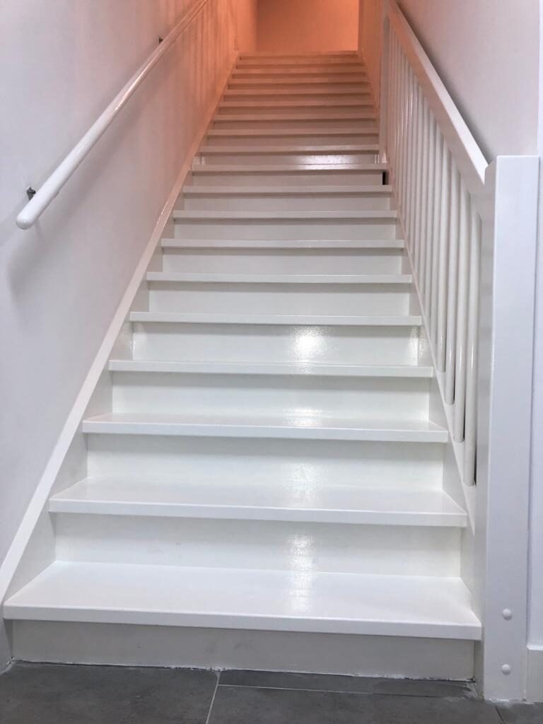Volledig gerenoveerde witgelakte trap met balustrade en handrail tussen begane grond en verdieping