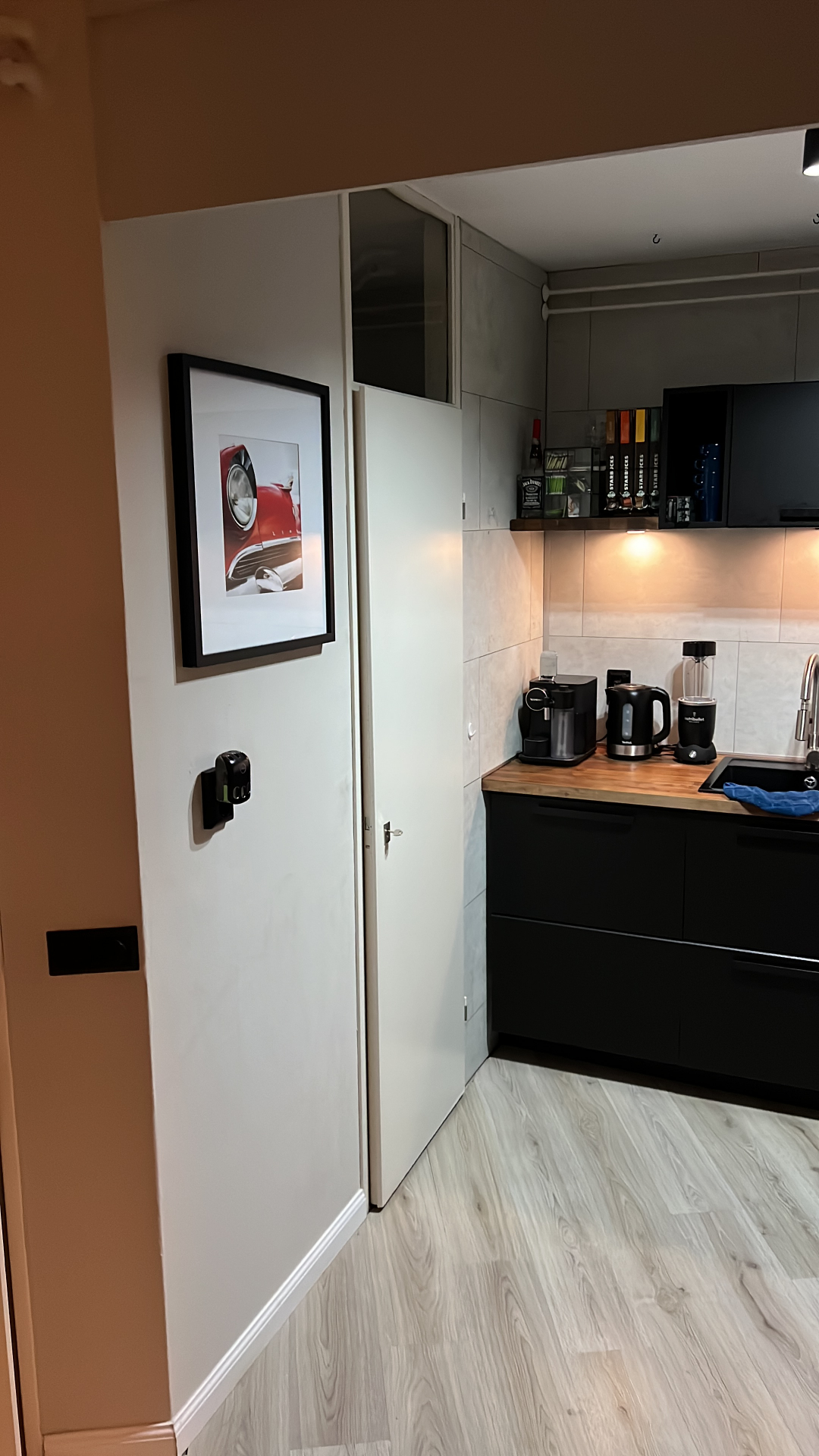Opgeleverde keuken met mat-zwarte greeploze fronten, houten werkblad, koffiehoek en houtlook PVC-vloer