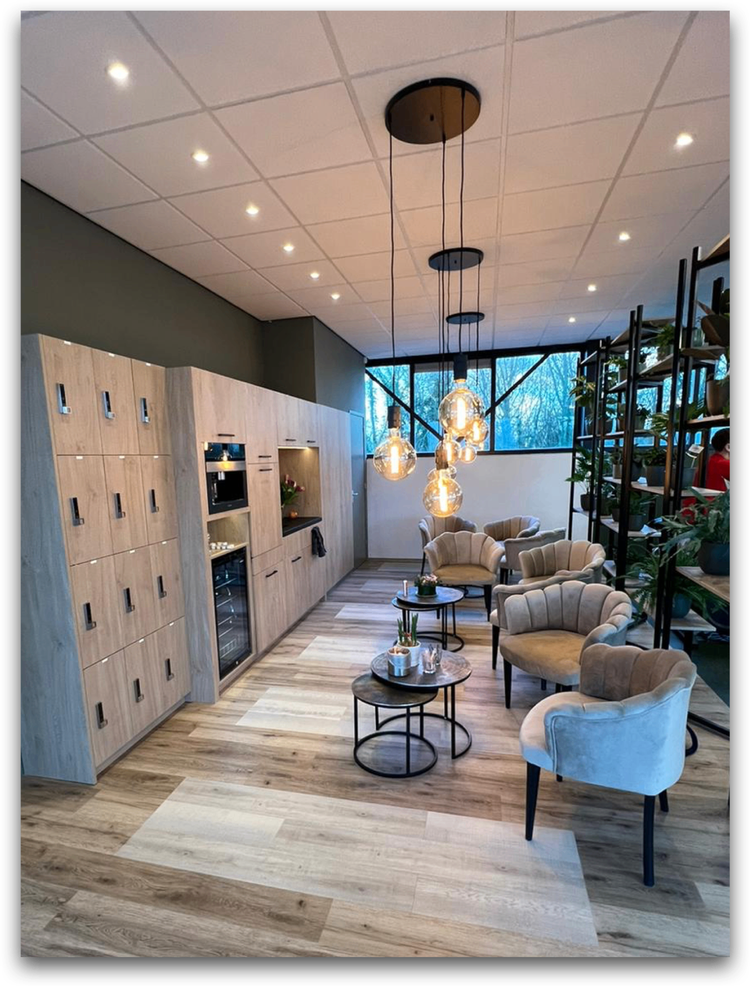 Opgeleverde lounge met lockerwand, koffiehoek en fauteuils onder design hanglampen