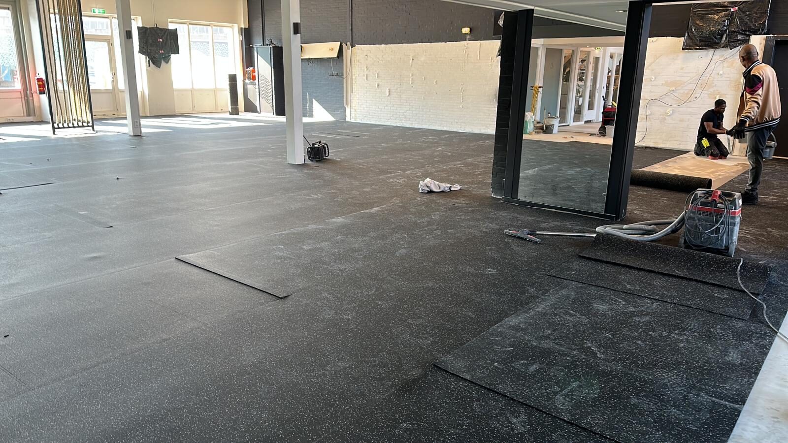 Sportvloer-opbouw — leggen van rubber sporttegels op gestripte casco vloer