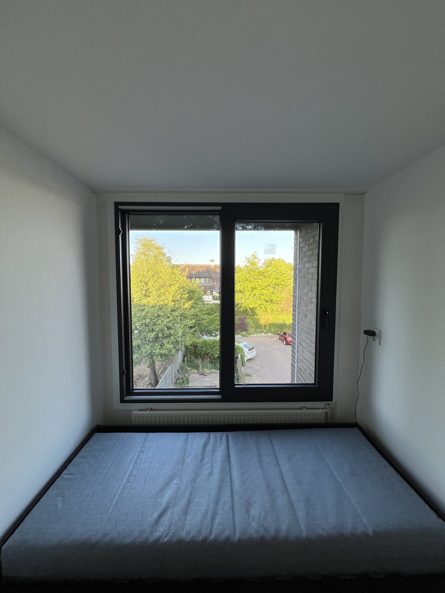 Slaapkamer met nieuw zwart aluminium raamkozijn — frontaal aanzicht met uitzicht op de straat