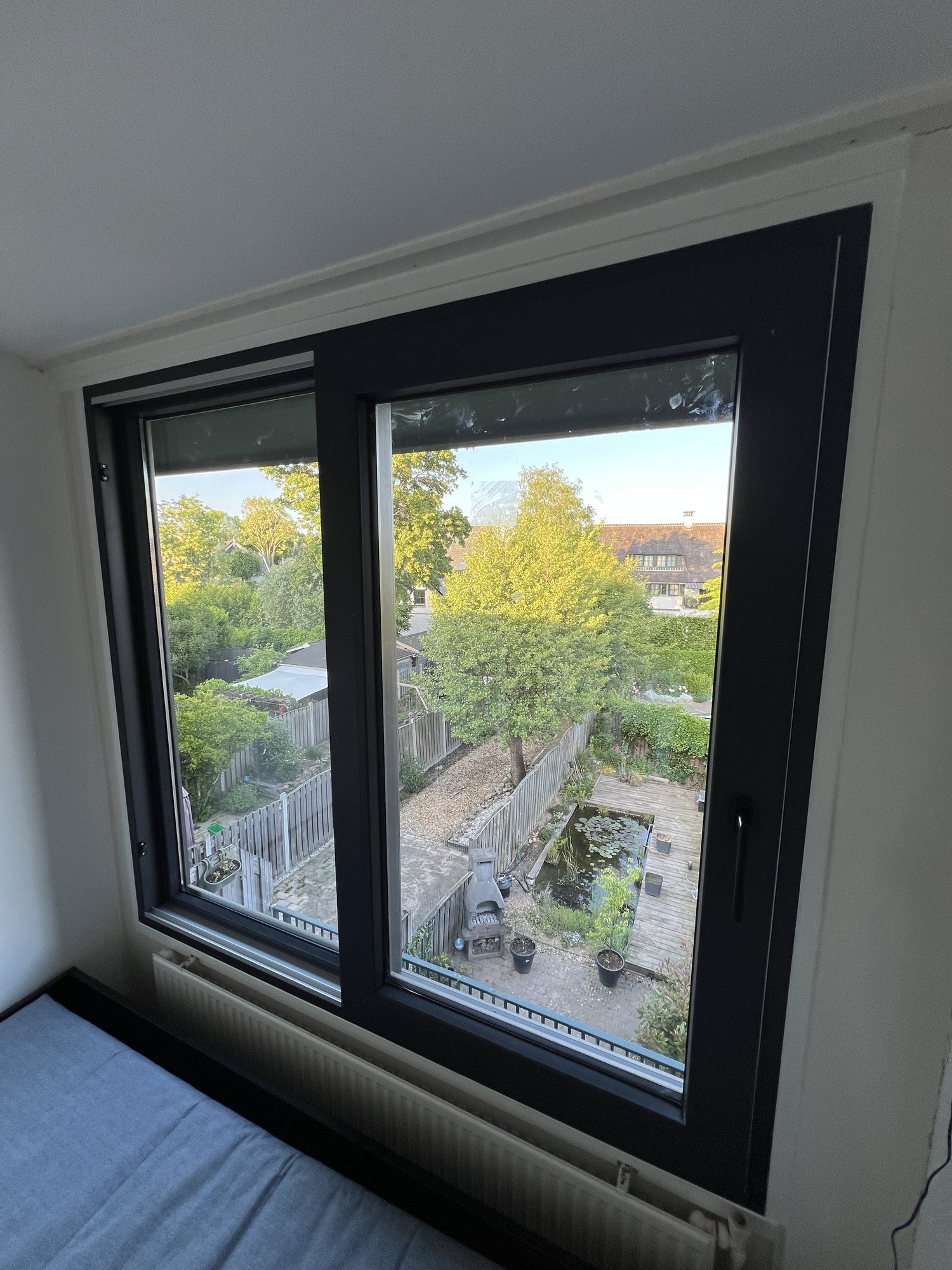 Detailopname van het nieuwe aluminium schuifraam met dubbele beglazing en uitzicht op de tuin