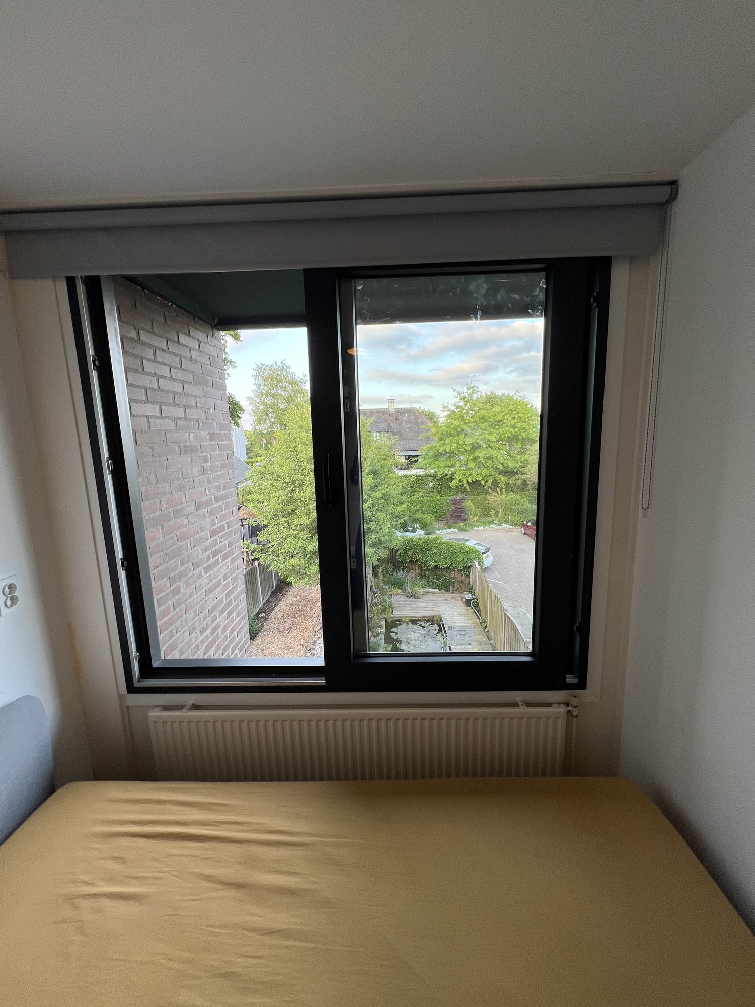 Slaapkamer met nieuw aluminium raamkozijn — uitzicht op bakstenen gevel en achtertuin