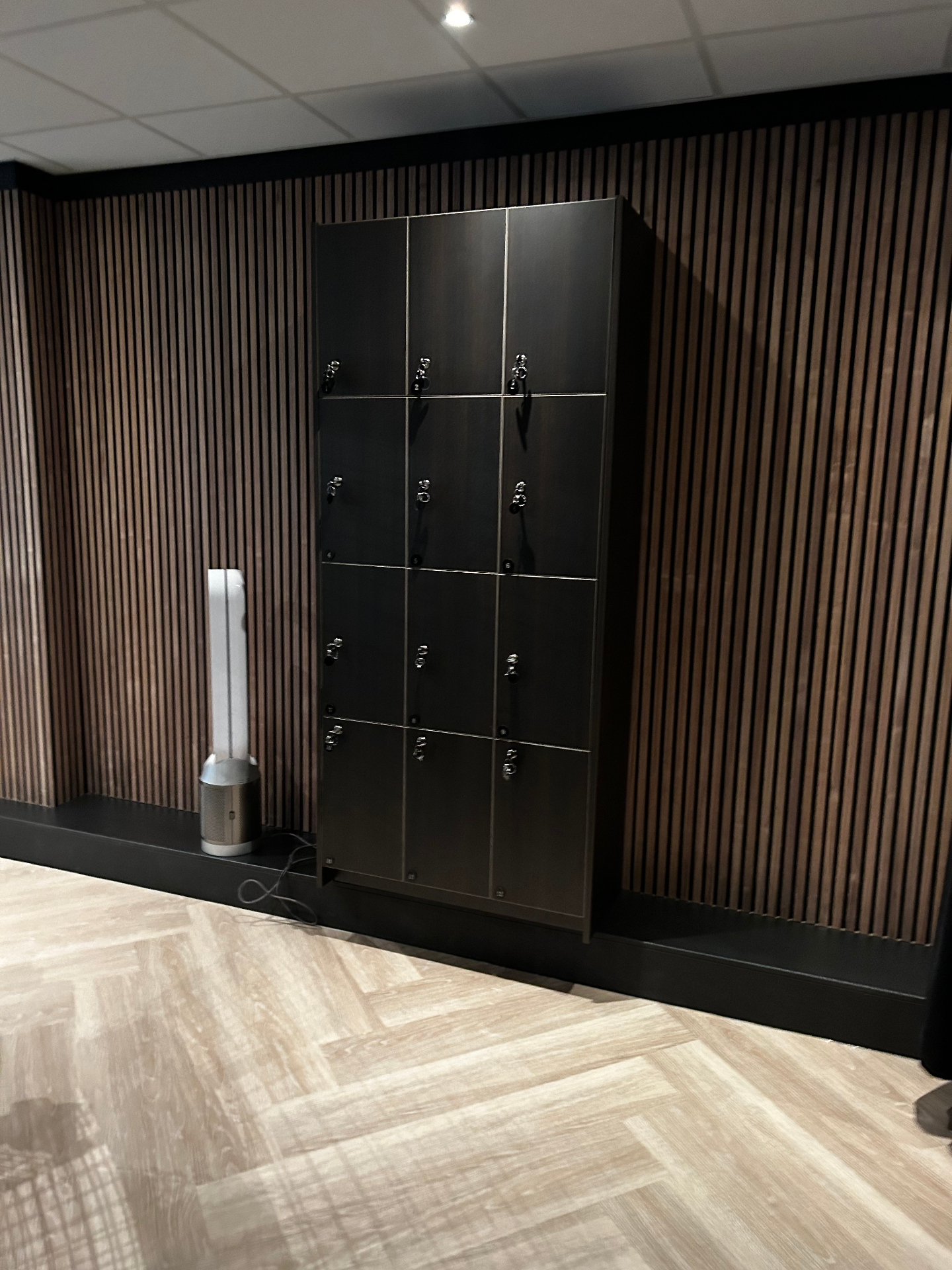 Maatwerk lockers in donker eiken/zwart geïntegreerd in latten­wand