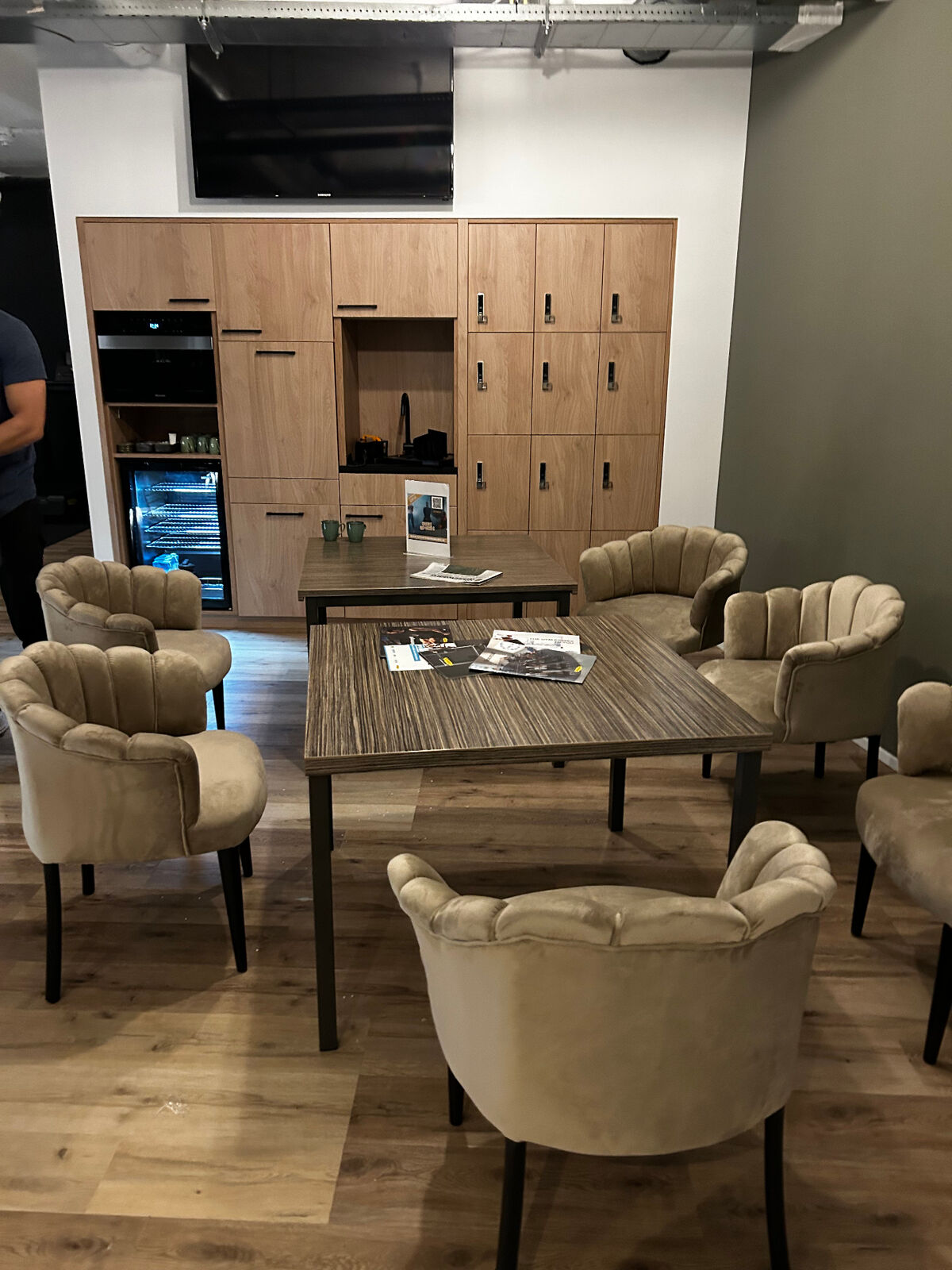 Lounge­zone met fauteuils, eiken kastenwand met lockers, koffie­hoek en TV