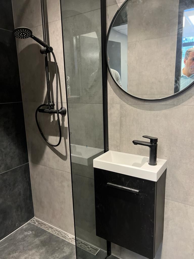 Powder room — kleine zwarte fonteinkast met ronde spiegel en zwarte regen­douche