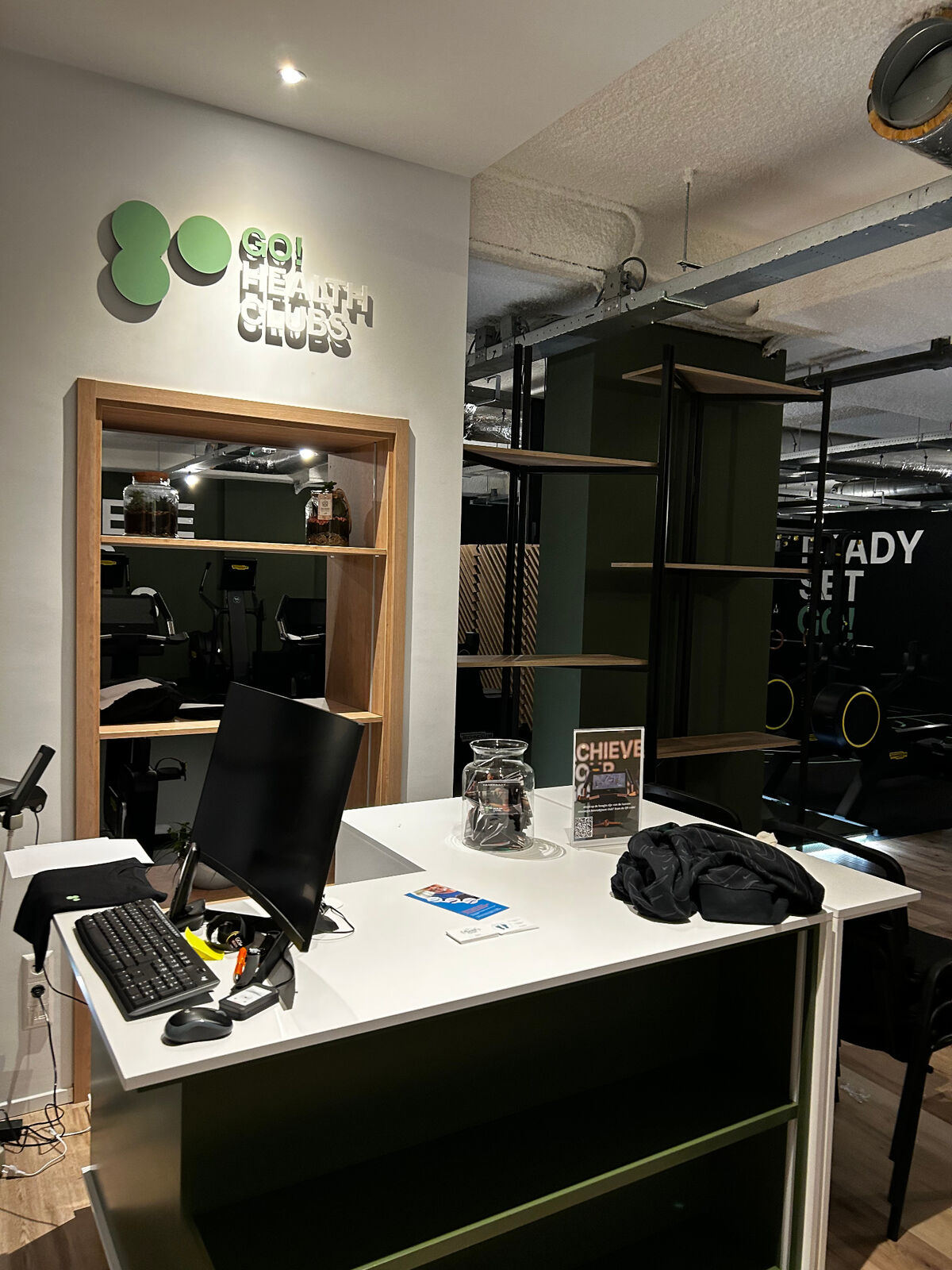 Receptie­balie met Go! Health Clubs signage en zwart-stalen room-divider