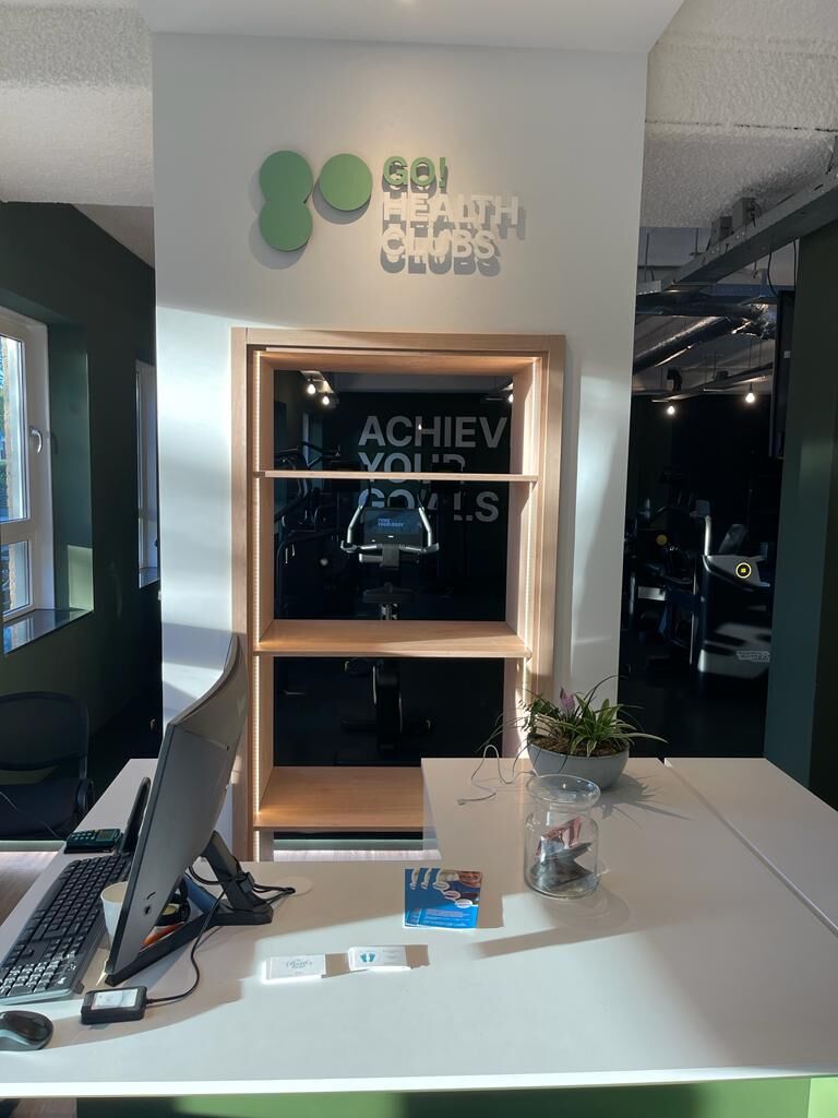 Opgeleverde receptie-balie met Go! Health Clubs signage en eiken displaykast