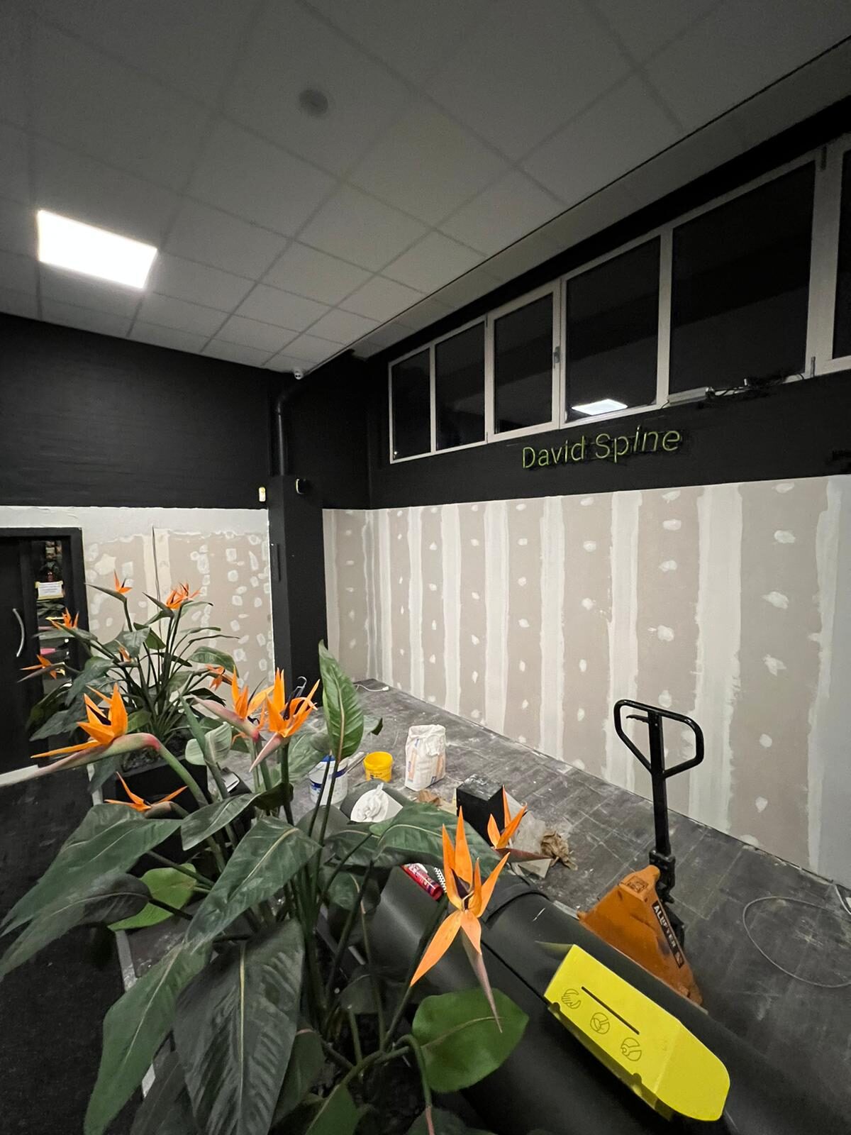 Receptiewand met geel-beige gestreept behang in opbouw onder David Spine signage
