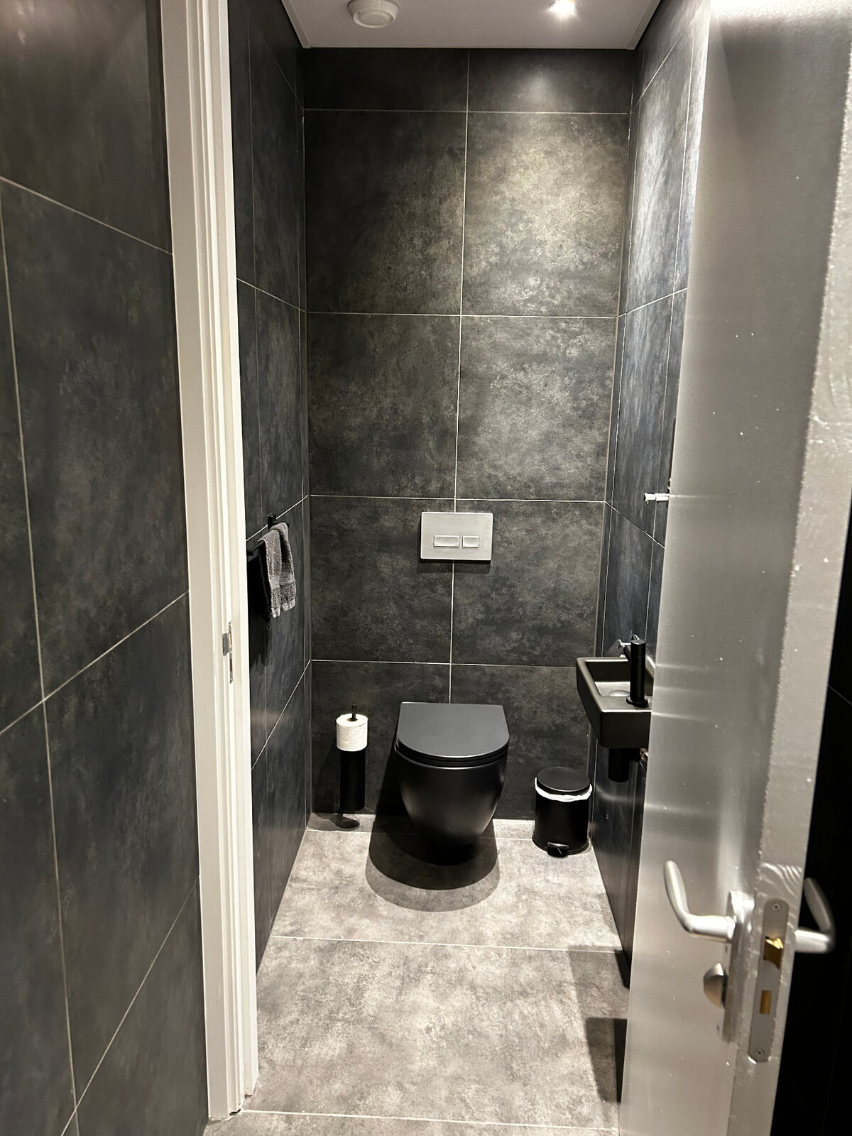 Modern sanitair met antraciet tegelwerk en mat-zwart toilet